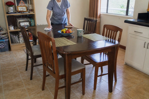 A woman wiping a dining table as part of professional maid services in Coachella, California.